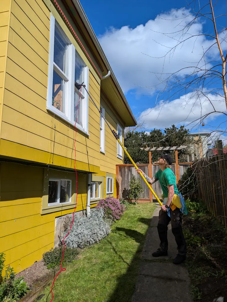 Axel, owner of Two Pines Window & Gutter Cleaning, cleaning windows at a Victoria, BC home