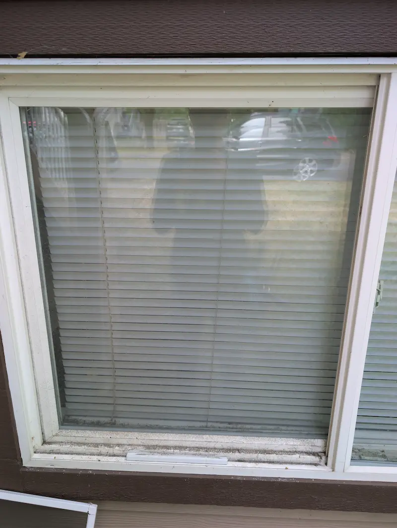 Basement window on a Victoria BC home with dirt and grime buildup on the frame and track before cleaning