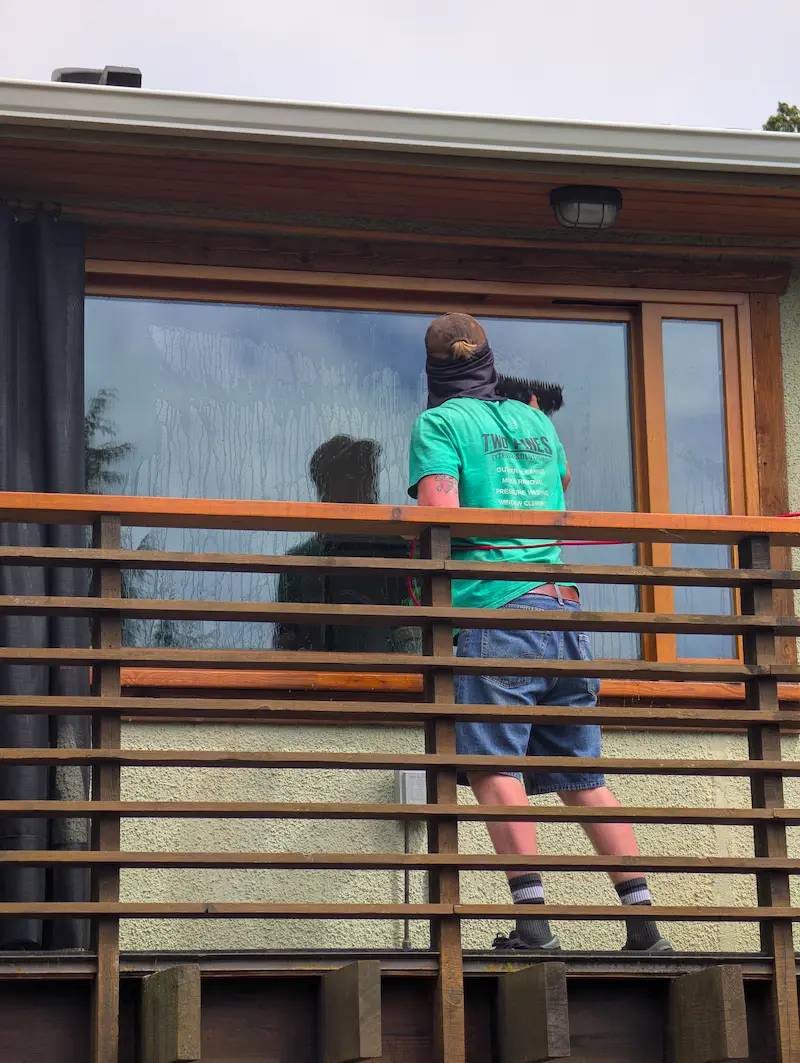 Two Pines technician using a water-fed pole with purified water to clean exterior windows on a Victoria BC home